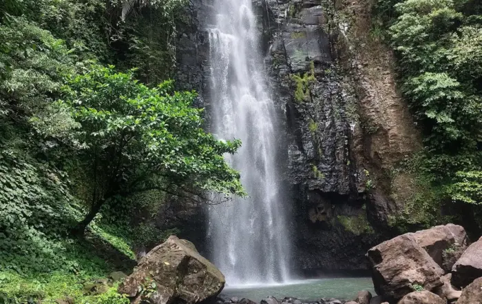 Air Terjun Tunan Talawaan setinggi 86 meter yang megah mengalir deras membelah tebing batu cadas hitam, dikelilingi rimbunnya hutan hijau tropis di Minahasa Utara
