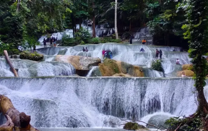 Wisatawan berdiri dan berendam di atas undakan batuan kapur bebas lumut Air Terjun Moramo Sulawesi Tenggara di tengah Hutan Suaka Alam Tanjung Peropa