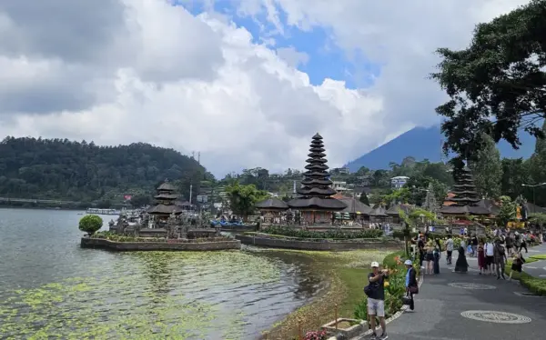 Kompleks Pura Ulun Danu Beratan yang eksotis berdiri di atas air danau yang tenang di kawasan dataran tinggi Bedugul Bali dengan latar kabut tipis.